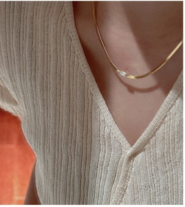 Detail of a minimalist gold snake chain necklace with a rectangular zircon pendant on neck