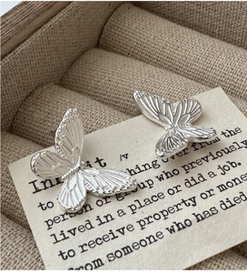 Detailed view of silver butterfly stud earrings with delicate carved wing textures