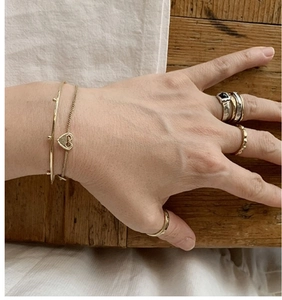 Detail showing stacked minimalist rings with a black gemstone and a hollow heart bracelet