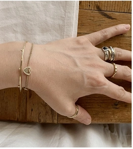 Close-up of a hand wearing minimalist S925 silver rings and heart pendant bracelet