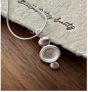 Macro detail of S925 sterling silver matte geometric pendant with engraved hallmark on snake chain