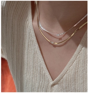 Detail of layered S925 sterling silver herringbone chains with baguette-cut zircon pendants