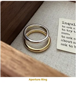 Polished silver and gold minimalist rings displayed in a rustic wooden jewelry box