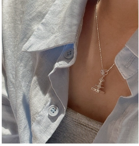 Close-up of S925 silver fountain pendant necklace worn over a blue linen shirt