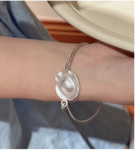 Detail of a minimalist S925 sterling silver cuff with matte textured irregular metal charm