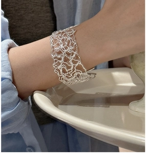 Detailed view of wide 925 sterling silver hollow mesh cuff bracelet on a female wrist
