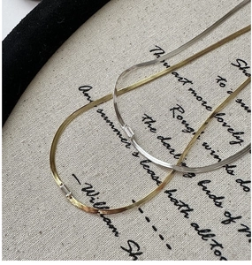 Macro shot of gold and silver flat snake chains with rectangular zircon crystal charms