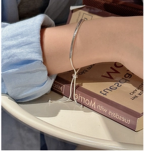Minimalist S925 sterling silver adjustable bracelet worn on wrist over a book