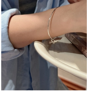 Minimalist S925 sterling silver matte bracelet worn by a model on a blue striped shirt