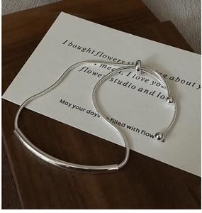 Macro detail of silver snake chain bracelet featuring a polished curved tube and bead accents