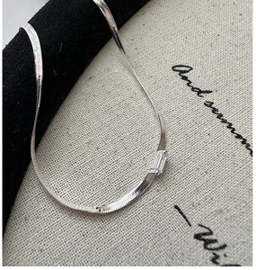 Detail of silver S925 snake chain featuring a rectangular baguette cut zircon pendant