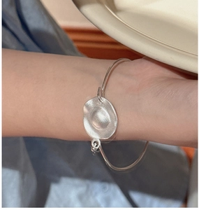 Close-up of matte S925 sterling silver cuff bracelet with hammered organic disc detail