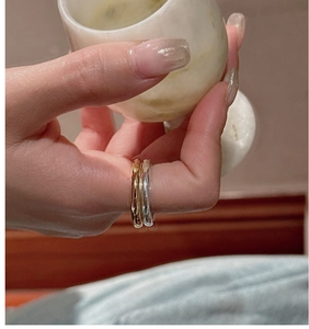 Close-up of polished gold and silver minimalist stackable rings on hand with marble cup