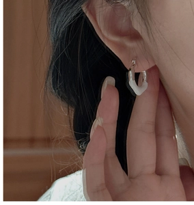 Detailed view of S925 silver earring with white enamel finish on a female model's ear
