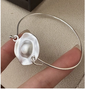 Detail of minimalist S925 sterling silver matte bangle held by fingers showing size
