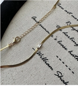 Close-up of golden snake chain necklace with rectangular zircon and lobster clasp