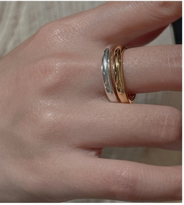 Close-up of interlocking three-tone rings in gold, silver, and rose gold on a finger
