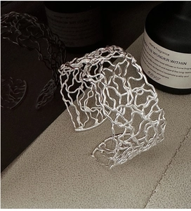 Macro shot of 925 silver wide open bangle with artistic hollow irregular grid design