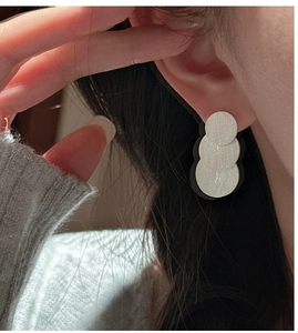 Close-up of S925 sterling silver layered disc earrings with a brushed metallic texture