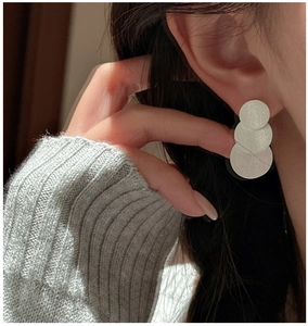 Close-up of layered S925 silver brushed disk earrings worn on a female model