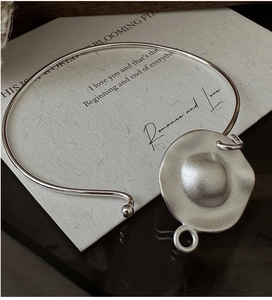 Macro detail of matte silver choker necklace with an abstract organic wave pendant