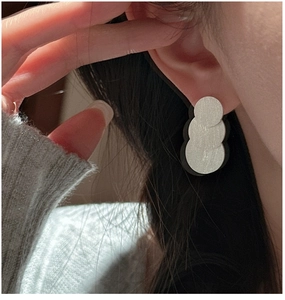 Macro shot of S925 sterling silver triple-layered brushed circle earrings on model