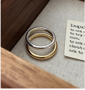 Close-up of minimalist gold and silver polished rings on a textured linen background