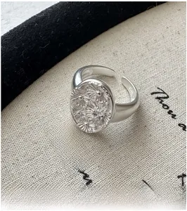 Macro detail of S925 sterling silver daisy ring with embossed floral pattern and zircon