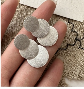 Detailed macro view of S925 sterling silver earrings with brushed matte metal circles