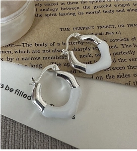 Detailed view of wavy S925 sterling silver hoop earrings with white resin inlay
