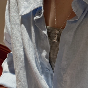 Elegant S925 sterling silver fountain tower pendant necklace worn over a blue linen shirt