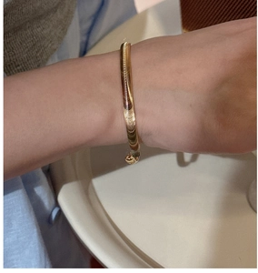 Gros plan détaillé d'un bracelet doré minimaliste à texture d'écailles sur le poignet