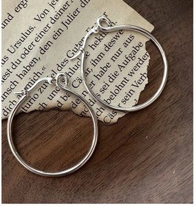 Dettaglio del marchio S925 su orecchini a cerchio in argento su sfondo di carta vintage