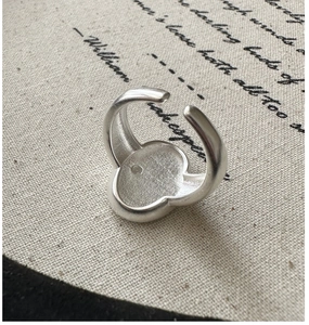 Detail of adjustable S925 silver ring with clover flower shape on beige linen textile