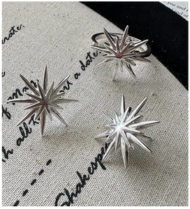 Macro shot of S925 sterling silver starburst earring and ring set on vintage fabric