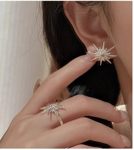 Close-up of S925 sterling silver starburst ring and earring set worn by a model