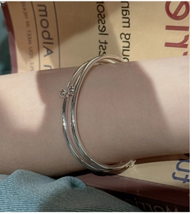 Detailed view of layered S925 silver bangles with small beads on a model's wrist