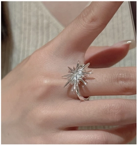 Macro shot of S925 sterling silver starburst ring showing metallic texture on finger