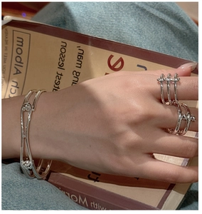 Detail of silver double-layered cuff bracelet and layered rings in modern industrial style