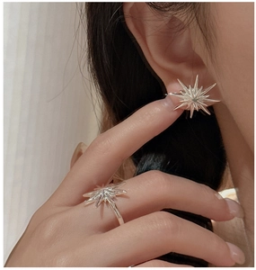 Detail of S925 sterling silver starburst earrings and matching ring set on a model