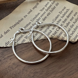 Orecchini a cerchio in argento sterling S925 lucido su sfondo di carta vintage