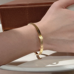 Bracelet jonc ouvert minimaliste en argent S925 doré poli au poignet du mannequin