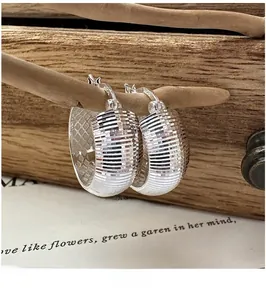 Détail macro de boucles d'oreilles créoles en argent S925 avec texture glace pilée