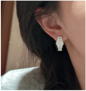 Gros plan de boucles d'oreilles en argent en forme de montre avec pavé de zircones