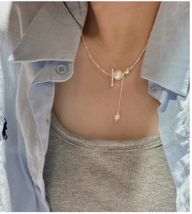 Detail of silver S925 necklace with T-bar, ring closure and a dangling drop pearl charm