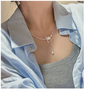 Detail of S925 sterling silver tassel necklace with white pearls on a model's neck
