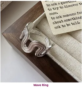 Macro shot of silver wave ring with irregular textured lines on a wooden jewelry tray