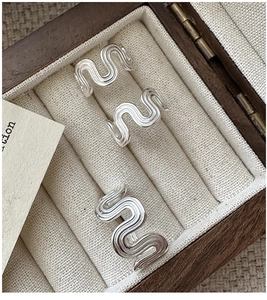 Macro shot of silver wavy textured rings in a vintage wooden jewelry display box