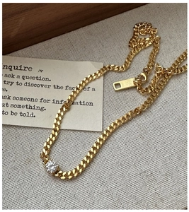 Macro shot of gold Cuban chain with center-set round zircon stone on fabric