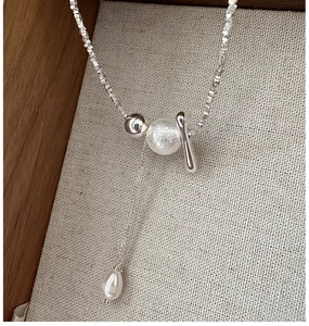 Macro detail of S925 sterling silver necklace with tassel pearl pendant on linen background